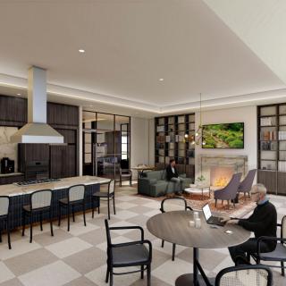 A modern open-concept kitchen and living area with a fireplace, seating, and a person using a laptop.