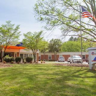A building with an American flag and parked vehicles under a clear sky.