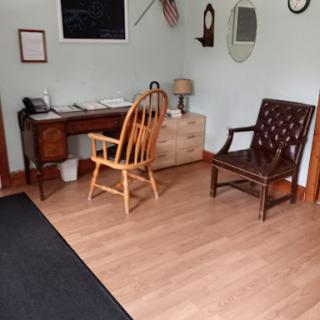 A cozy and inviting interior featuring a wooden desk, two chairs, and a light-colored floor.