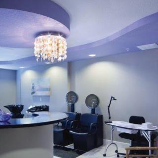 A modern salon interior featuring hair dryer chairs and a manicure station under an elegant chandelier.