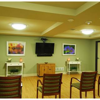 A well-lit conference room with chairs arranged facing a wall-mounted television and colorful artwork.