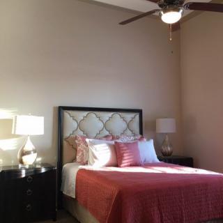 A cozy bedroom with a well-made bed, matching bedside tables, and ambient lighting.