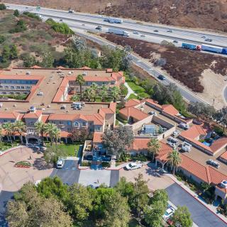 Aerial view of a large building complex near a highway, surrounded by trees.