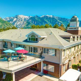 A scenic view of a building with a rooftop deck and mountains in the background on a sunny day.