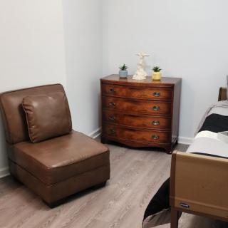 A cozy bedroom corner featuring a leather chair and a wooden dresser.