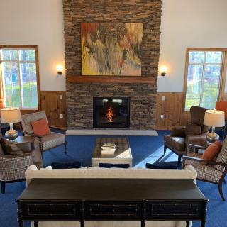 A cozy living room with a stone fireplace, modern seating, and large windows.
