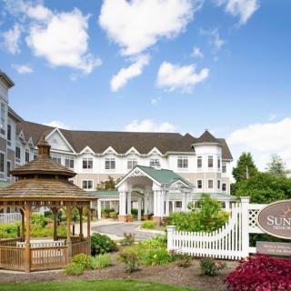 A scenic view of a hotel building with a gazebo and landscaped garden under a blue sky.