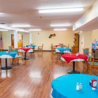 A spacious dining area with tables and chairs, decorated with red and blue tablecloths.