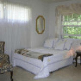 A cozy bedroom with a neatly made bed, window, and decorative accents.