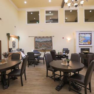 A cozy dining area with round tables, chairs, and warm lighting.
