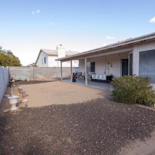 A spacious backyard patio area with gravel and a view of the house.