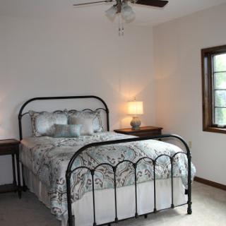 A cozy and minimalistic bedroom featuring a metal bed frame, soft bedding, and natural light.