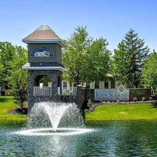 A serene view featuring a decorative water fountain surrounded by lush greenery in a residential community.