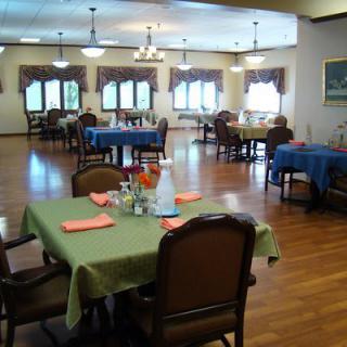 A spacious dining room with neatly arranged tables and chairs, featuring a wooden floor and elegant decor.