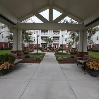 A landscaped courtyard with benches leading to a multi-story residential building.