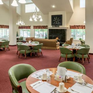 A spacious dining area with multiple tables and chairs, featuring a cozy interior design.