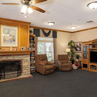 A cozy living room featuring a fireplace, armchairs, and a television.
