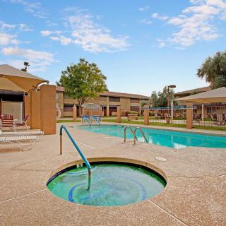 A sunny day at an outdoor pool and hot tub area in a resort.