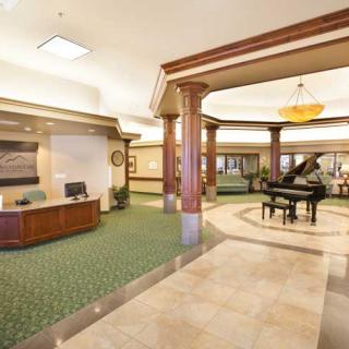 An elegant hotel lobby with a reception desk and grand piano.