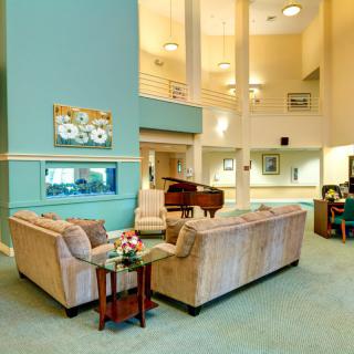 A spacious lobby featuring comfortable seating and a grand piano, with modern decor.