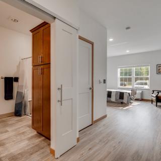 A modern interior featuring a bedroom and adjacent bathroom with hardwood flooring and ample natural light.