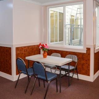 A small dining area with a table and chairs, featuring flowers and a window.