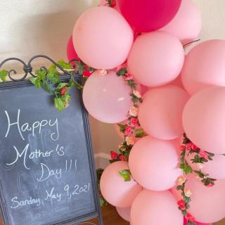A festive Mother's Day decoration with pink balloons and a chalkboard sign.