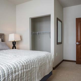 A minimalist bedroom with a bed, lamp, and an empty closet.