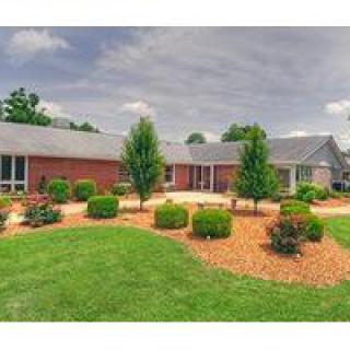 A single-story brick house with a well-maintained garden and lawn.