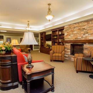 A cozy living room featuring a stone fireplace, comfortable armchairs, and built-in bookshelves.