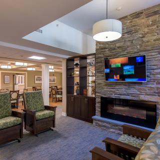 A cozy living room interior with a modern fireplace and television, surrounded by comfortable seating and warm lighting.