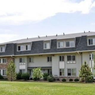 A residential apartment building with a well-maintained lawn in the foreground.
