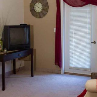 A cozy living room corner featuring a vintage television on a table beside a decorative clock and curtains.