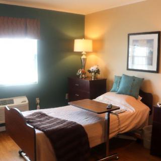 A well-lit bedroom with a hospital bed and cozy furnishings.