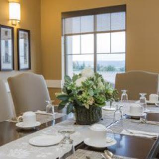 An elegantly set dining table with a floral centerpiece and neatly arranged dishes and glasses.