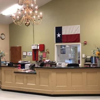 A welcoming reception area featuring a Texas flag and elegant chandelier.