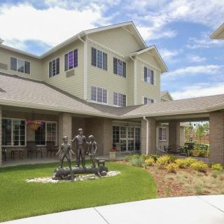 A residential building with a well-landscaped yard and a statue in front.