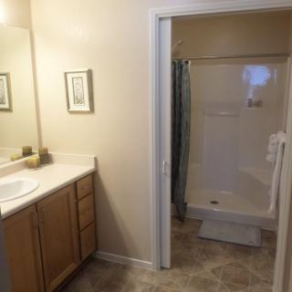 A clean and simple bathroom with a shower, sink, and wooden cabinets.