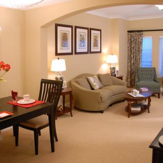 A cozy living room with a connected dining area, featuring comfortable furniture and warm lighting.