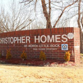 A brick sign for Christopher Homes surrounded by trees and landscaping.