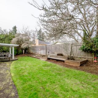 A serene backyard with a well-maintained lawn, wooden deck, and mature trees.
