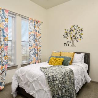 A cozy bedroom with colorful curtains and decorative pillows.