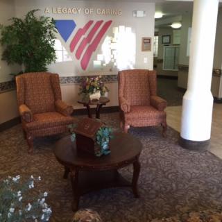 A welcoming lobby with two armchairs and a table, decorated with plants and patriotic wall art.