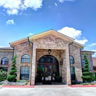 A brick building with a grand entrance under a blue sky with fluffy clouds.