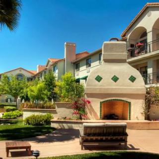 A beautiful apartment complex with a central outdoor fireplace and landscaped garden.
