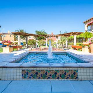 A beautiful courtyard with a central fountain and tiled design under a bright blue sky.