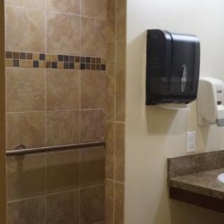 A bathroom with tiled walls, a paper towel dispenser, and a hand dryer.