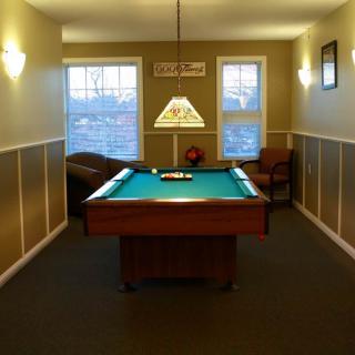 A cozy billiard room with a pool table centered under warm lighting.