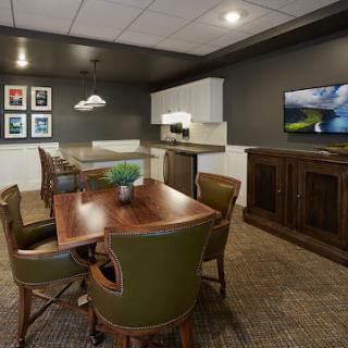 A cozy office meeting room featuring a wooden table, comfortable chairs, and a television.