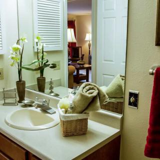 A well-decorated bathroom with a sink, mirror, and towels neatly arranged.